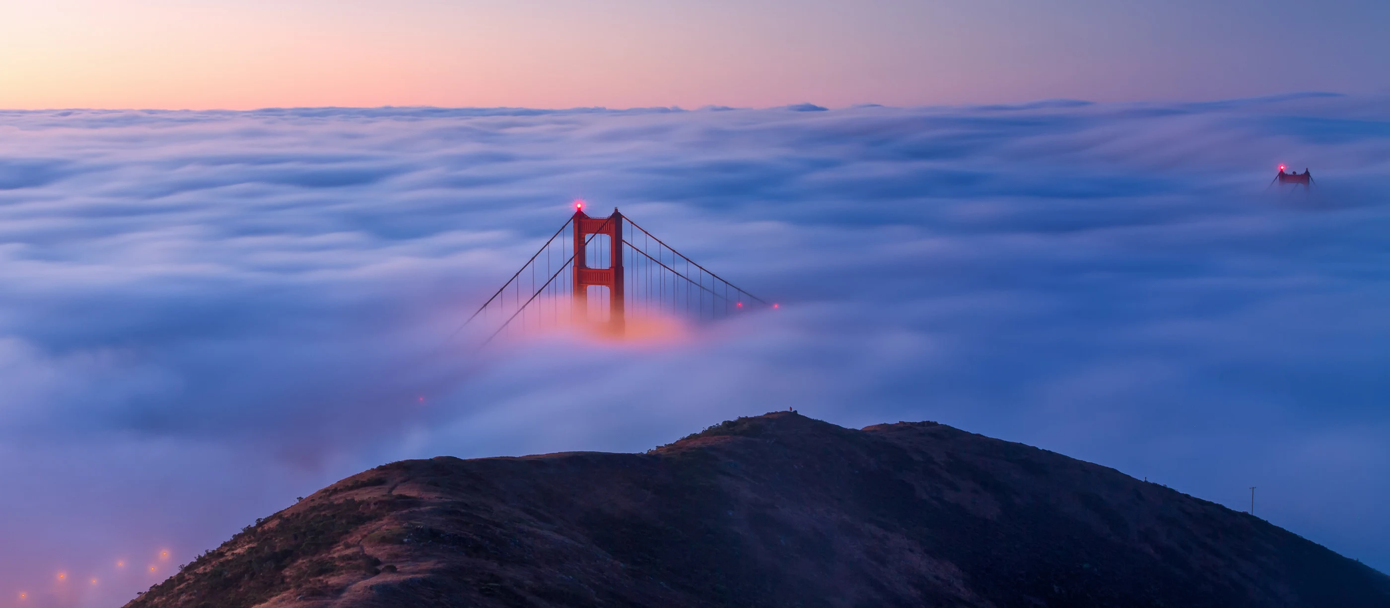 Una torre del Golden Gate emerge sobre la niebla de San Francisco al atardecer.